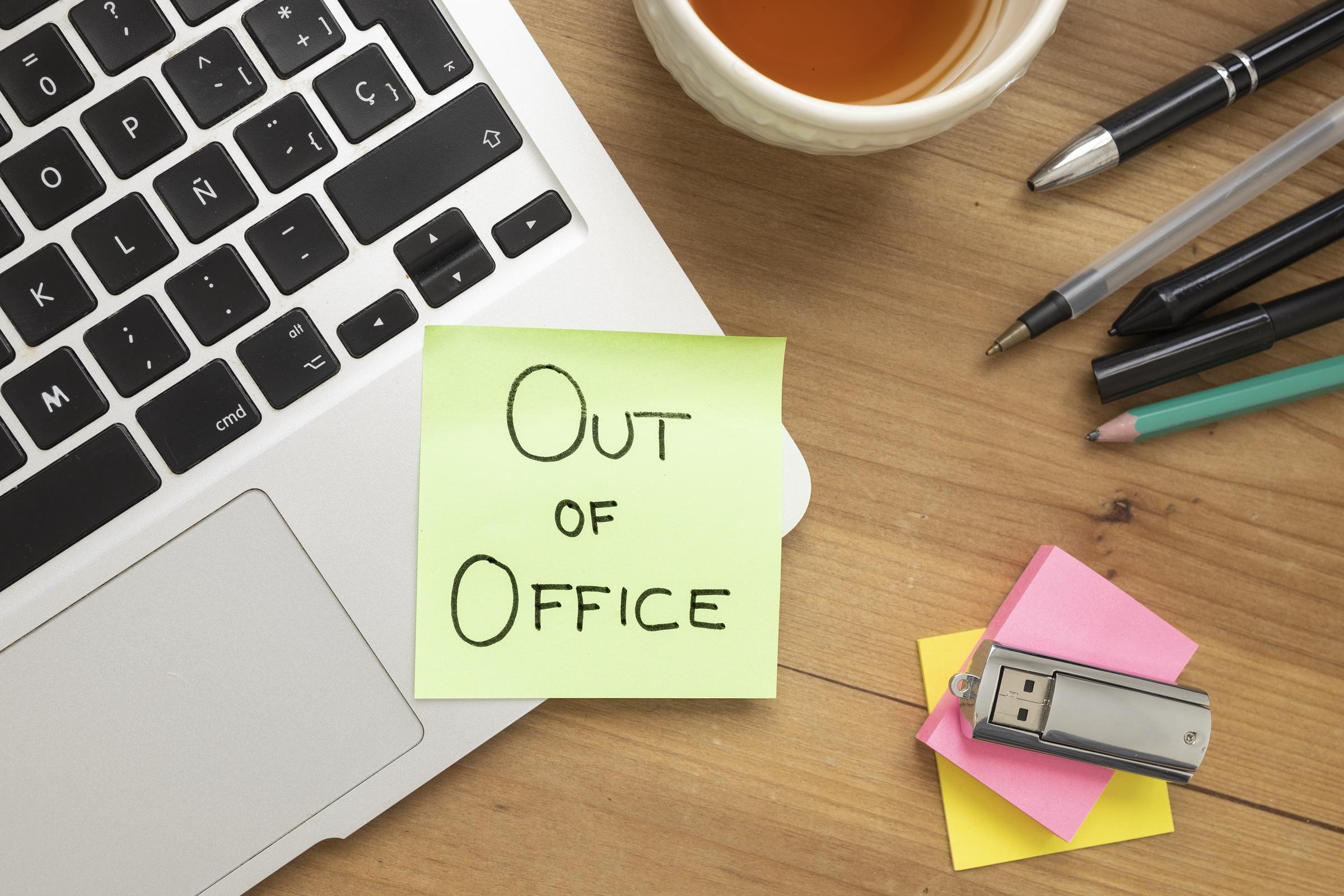 An "Out of Office" sticky note taped to a laptop | Source: Getty Images