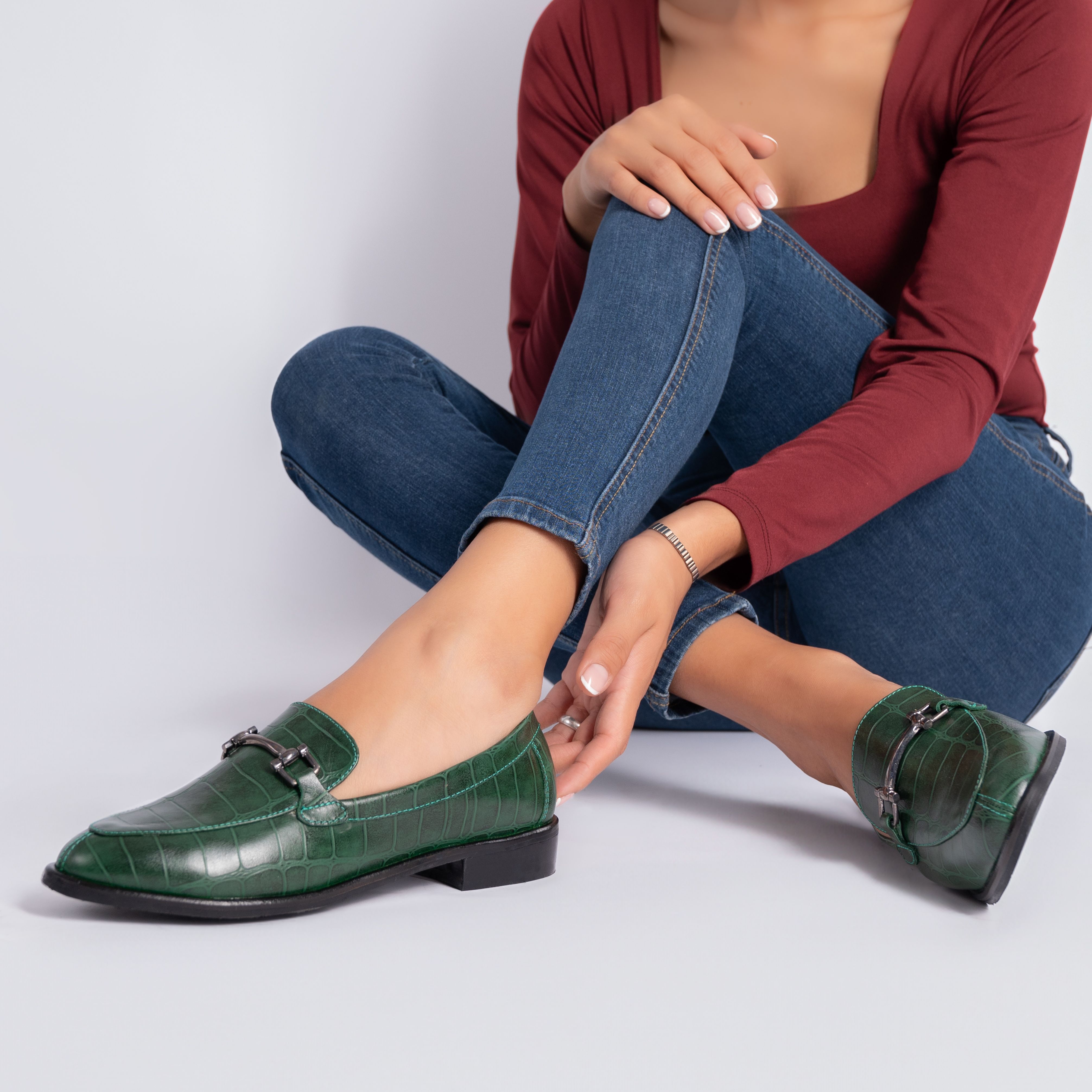 A seated woman wearing loafers with jeans | Source: Pexels