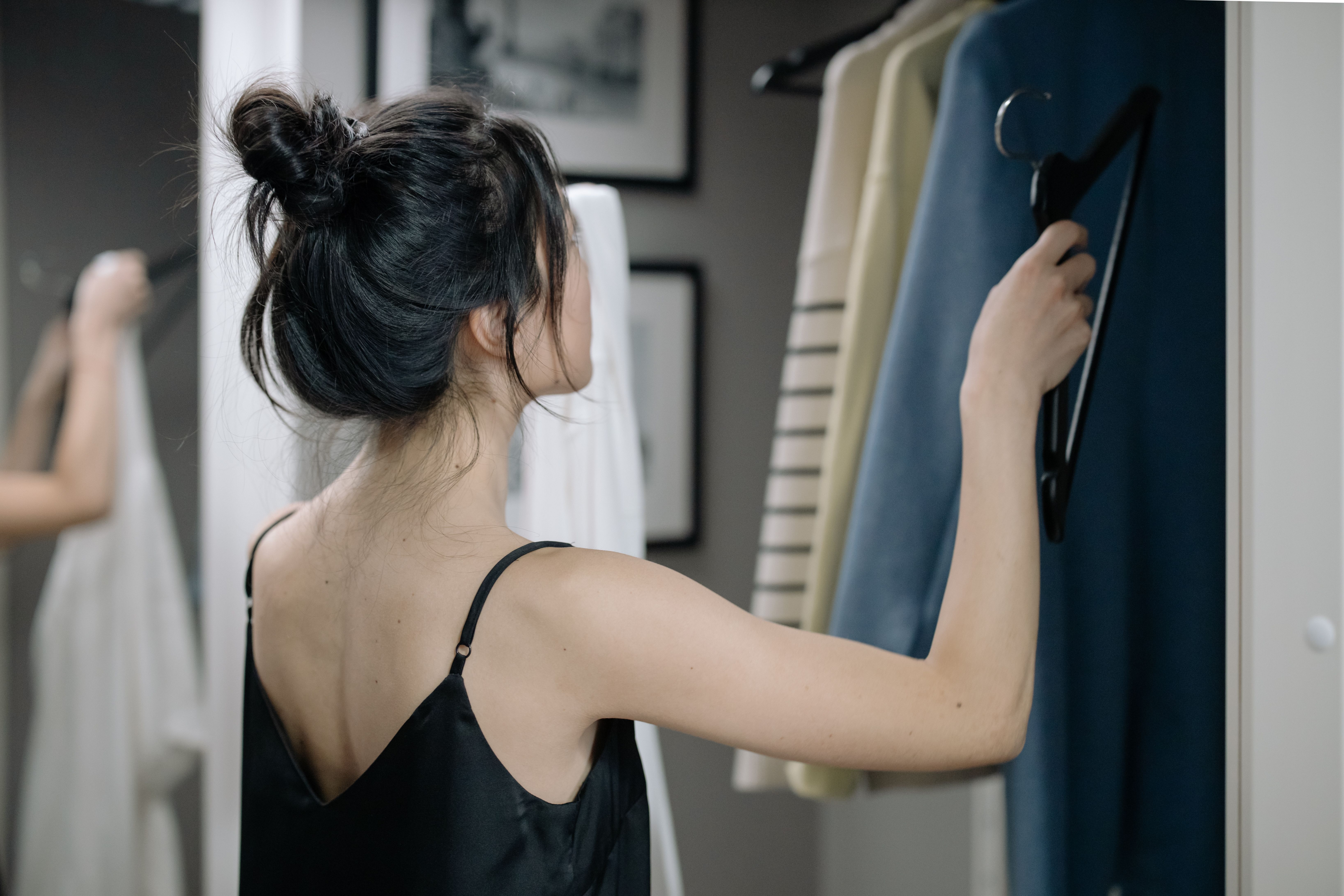 Woman staring at clothes in a closet | Source: Pexels