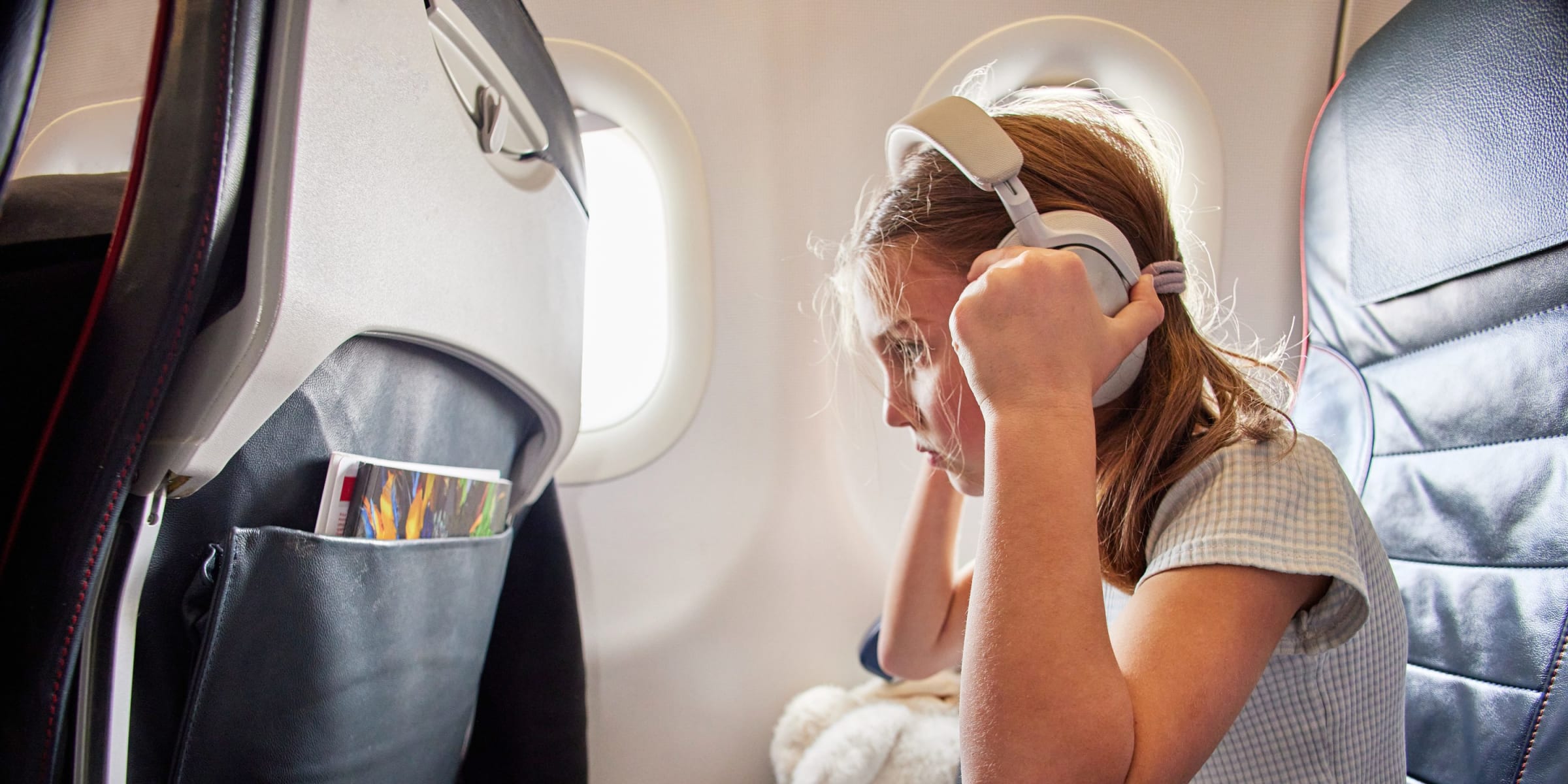 A young girl listening to music on a plane | Source: Getty Images