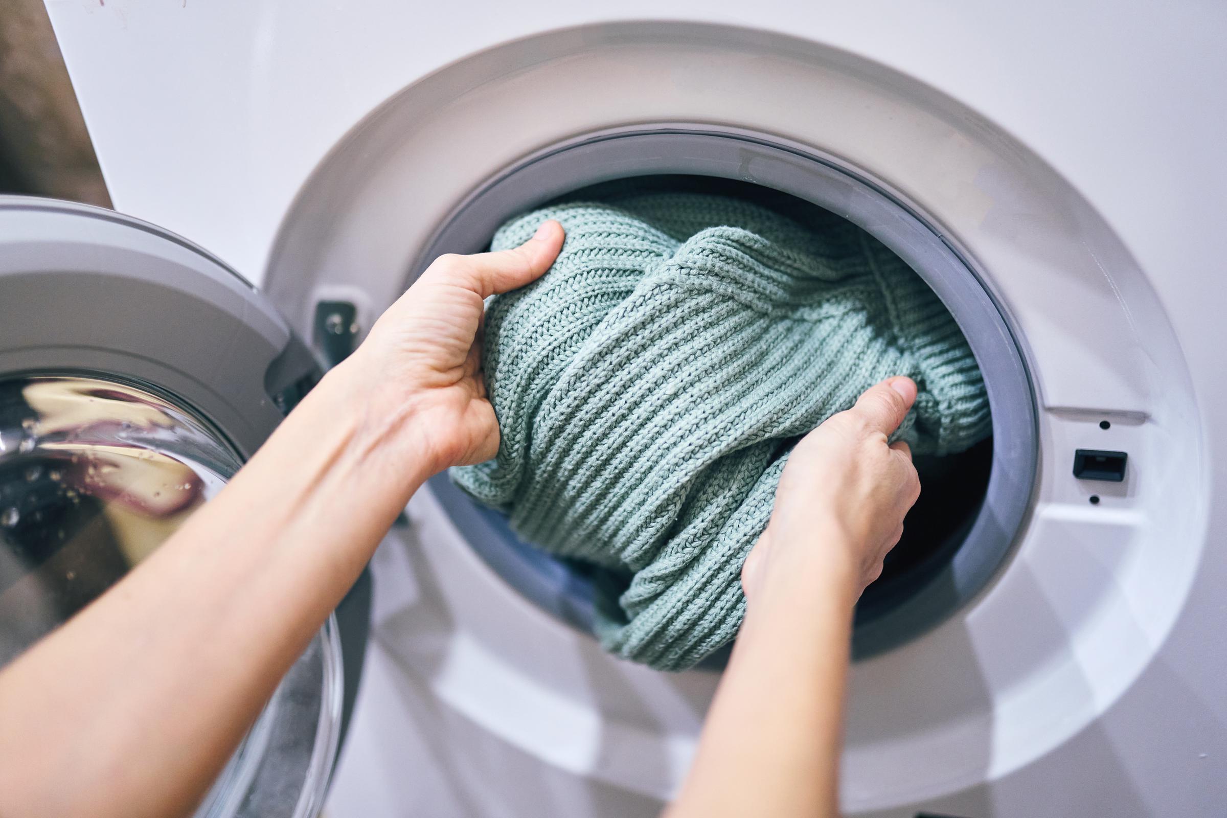 A woman putting her sweater into a washing machine | Source: Getty Images