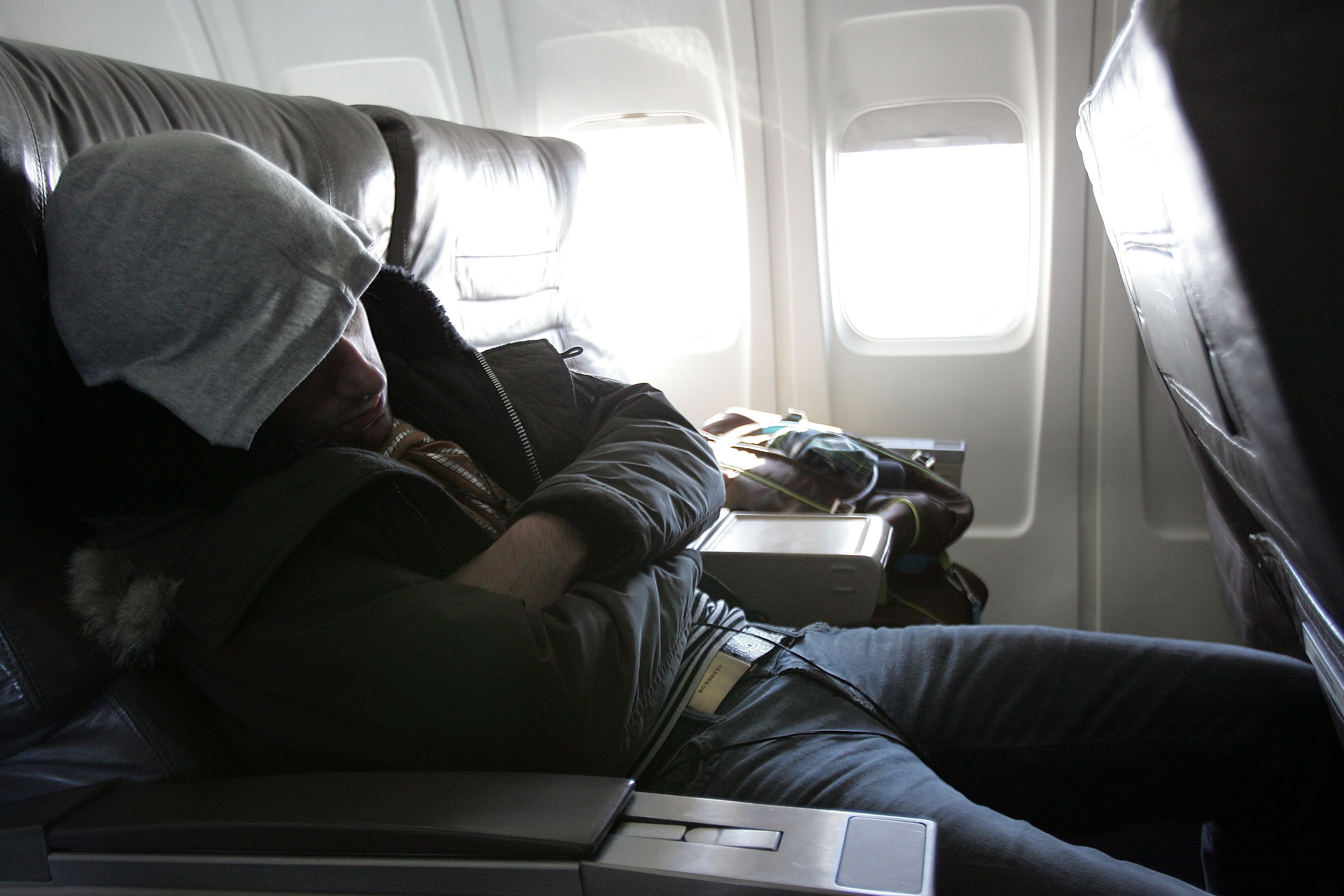 Man in a hoodie sleeping in an airplane | Source: Getty Images