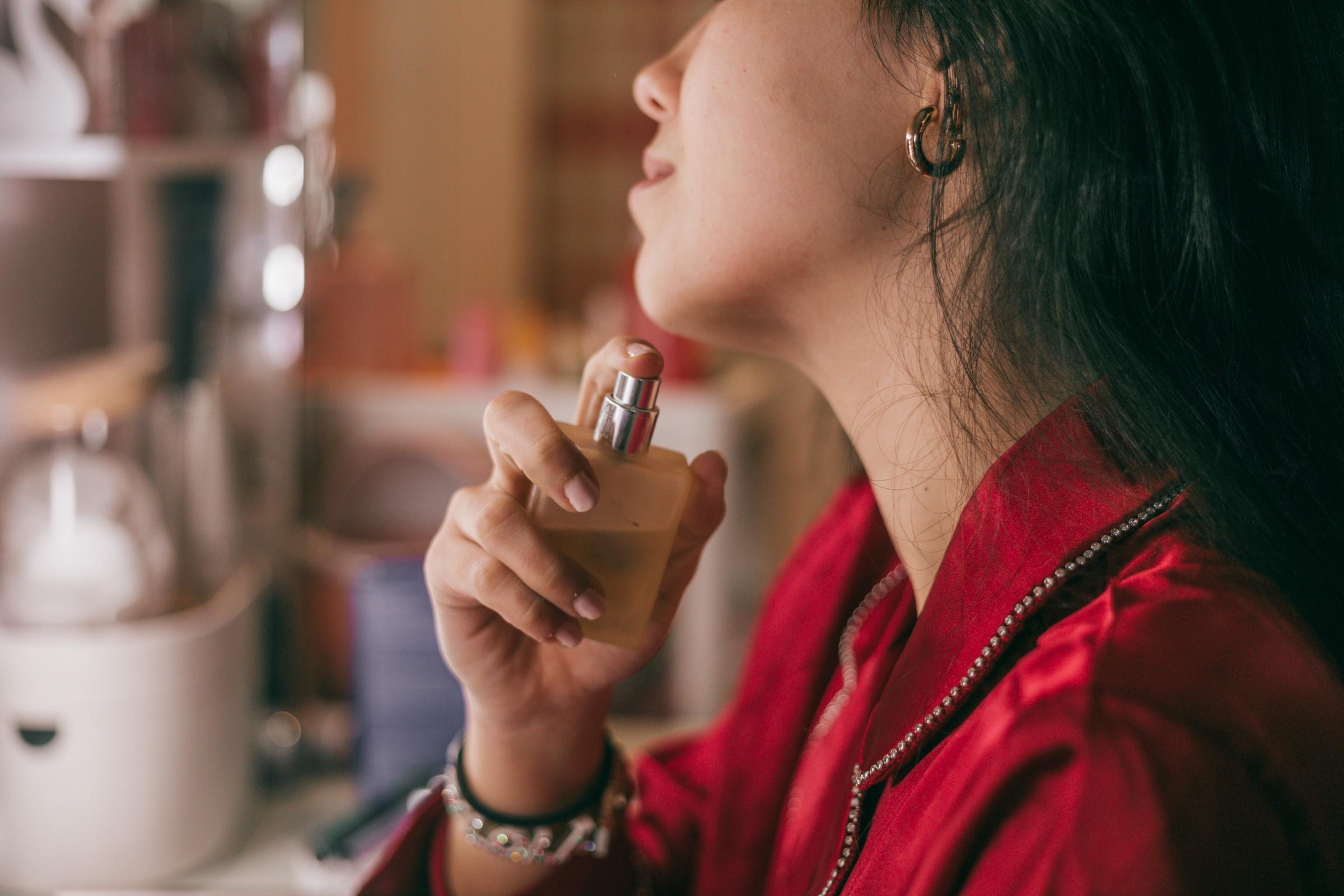 A woman spraying perfume on her neck | Source: Getty Images
