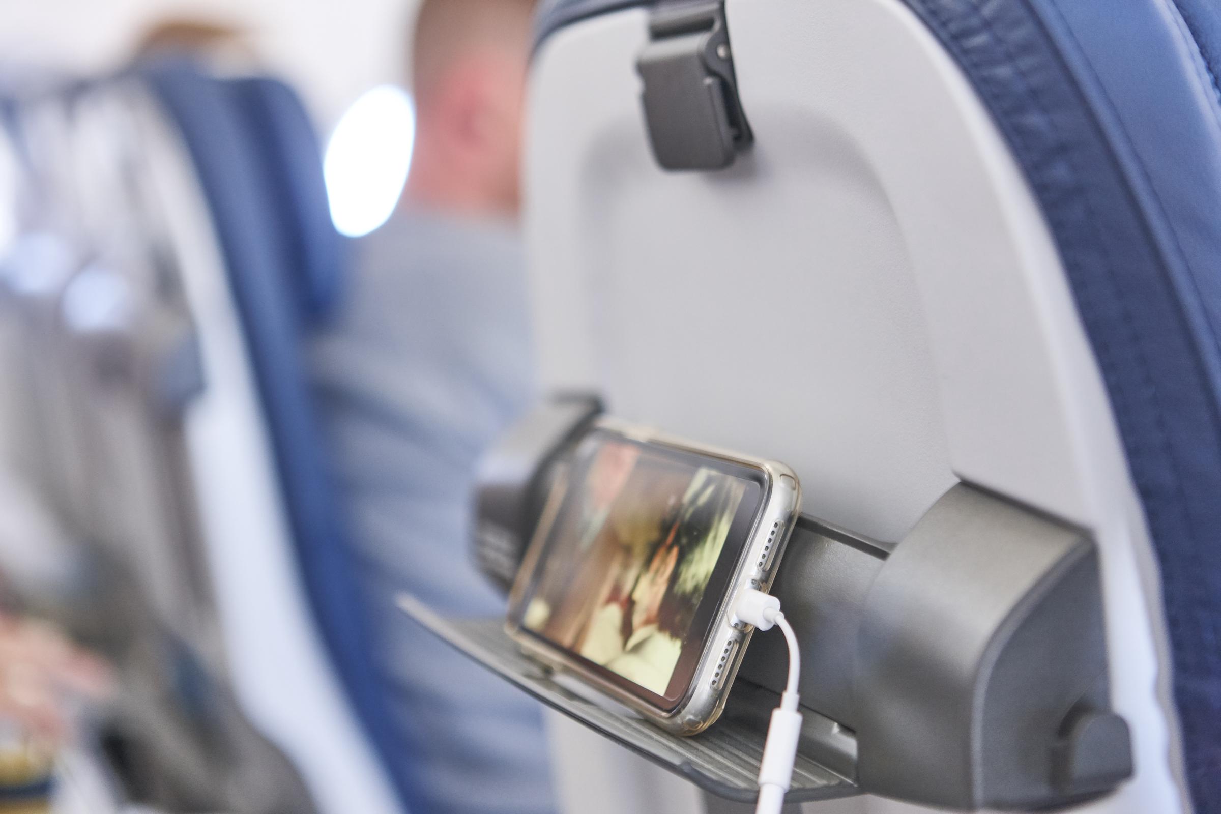 A passenger charging their phone on a plane | Source: Getty Images