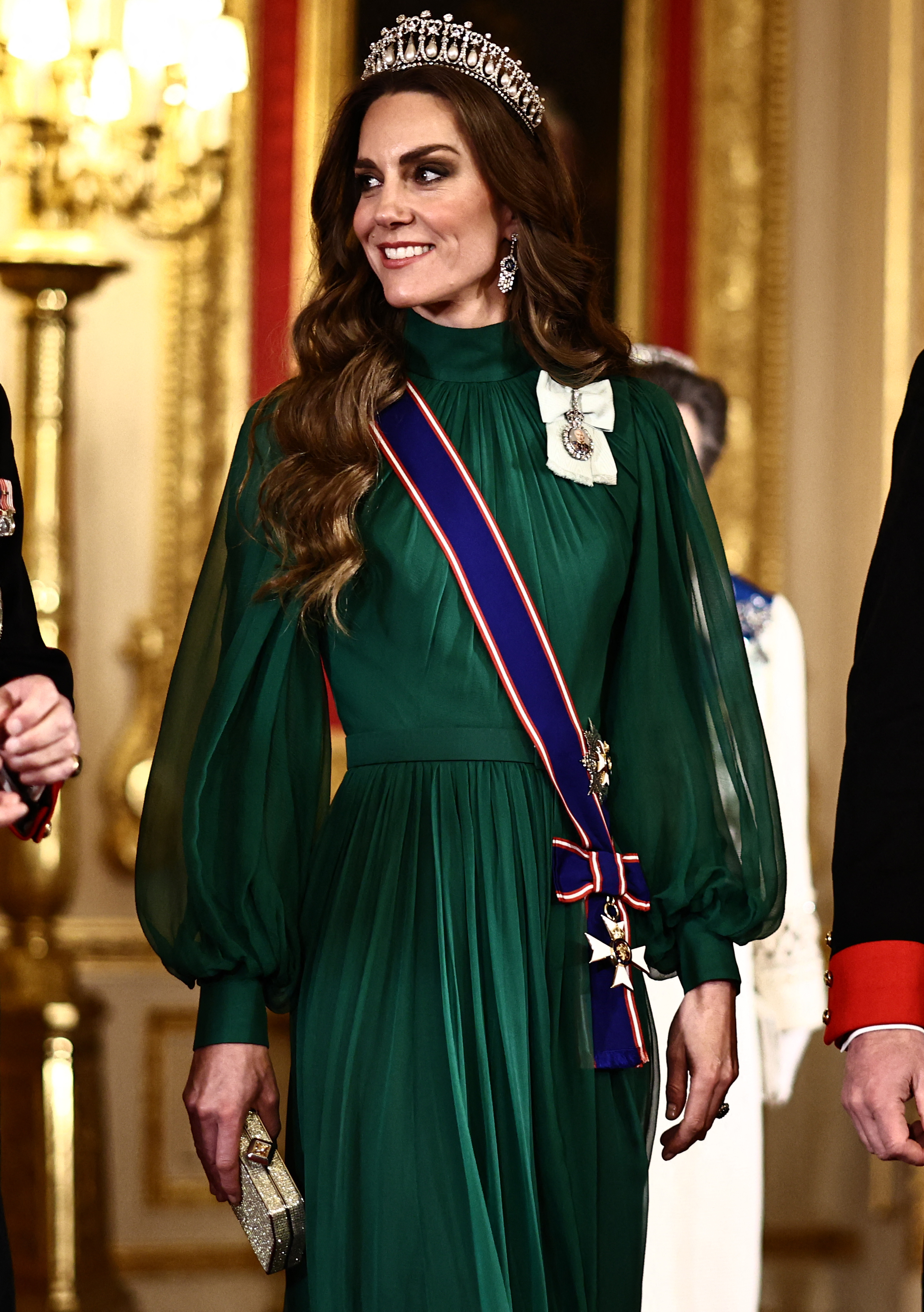 Catherine, Princess of Wales, arrives for the State Banquet in St. George's Hall at Windsor Castle on March 18, 2026, honoring the President of Nigeria. Radiating evening glamour, Catherine wears a flowing emerald-green chiffon gown by Emilia Wickstead featuring a gathered high neckline and billowing sheer bishop sleeves, accessorized with Queen Mary's Lover's Knot Tiara, diamond drop earrings, a glittering gold clutch, the Royal Victorian Order sash, and King Charles III's Royal Family Order. | Source: Getty Images