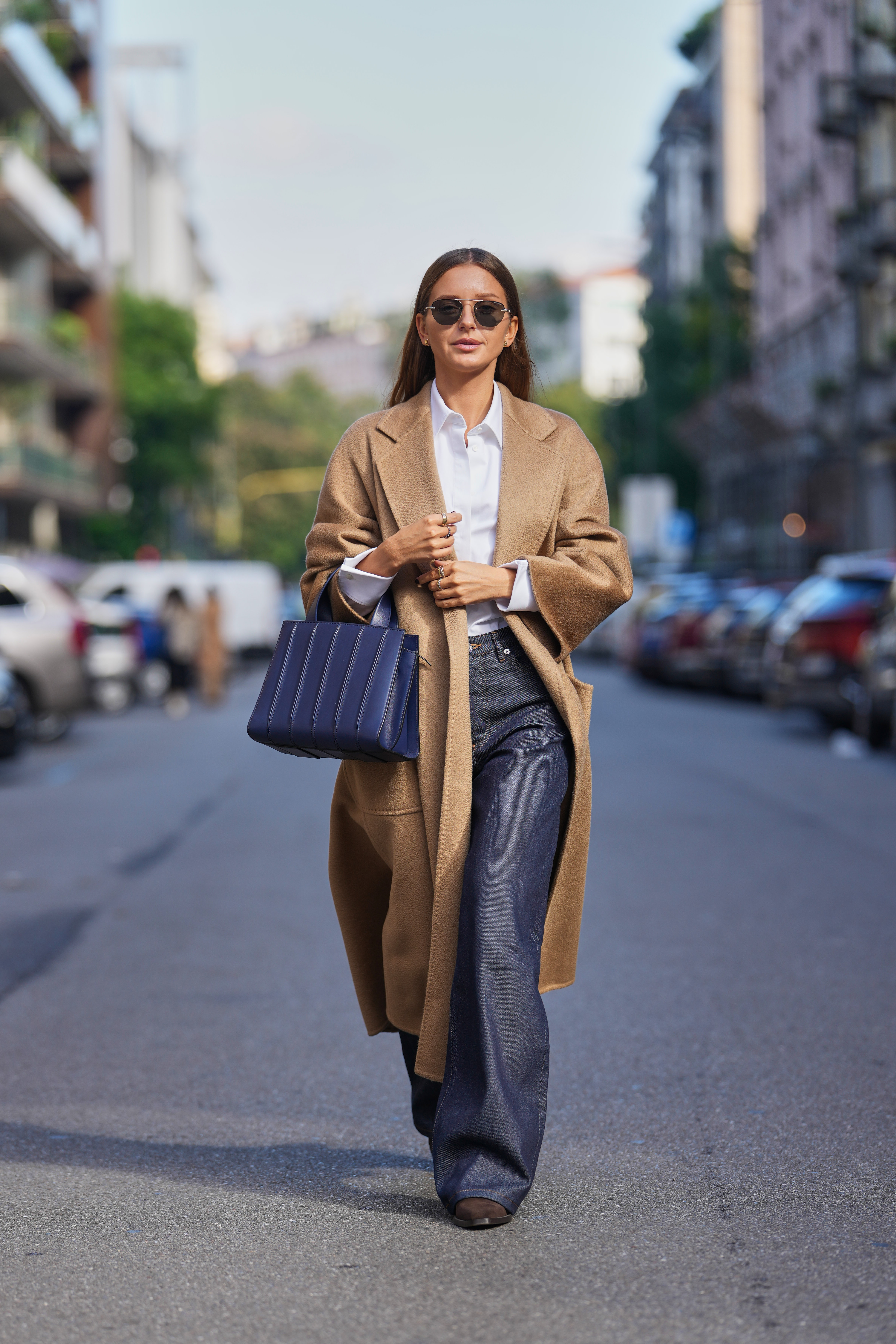 Diane Batoukina wearing dark indigo denim wide-leg jeans with a white white cotton button-up shirt and camel coat | Source: Getty Images