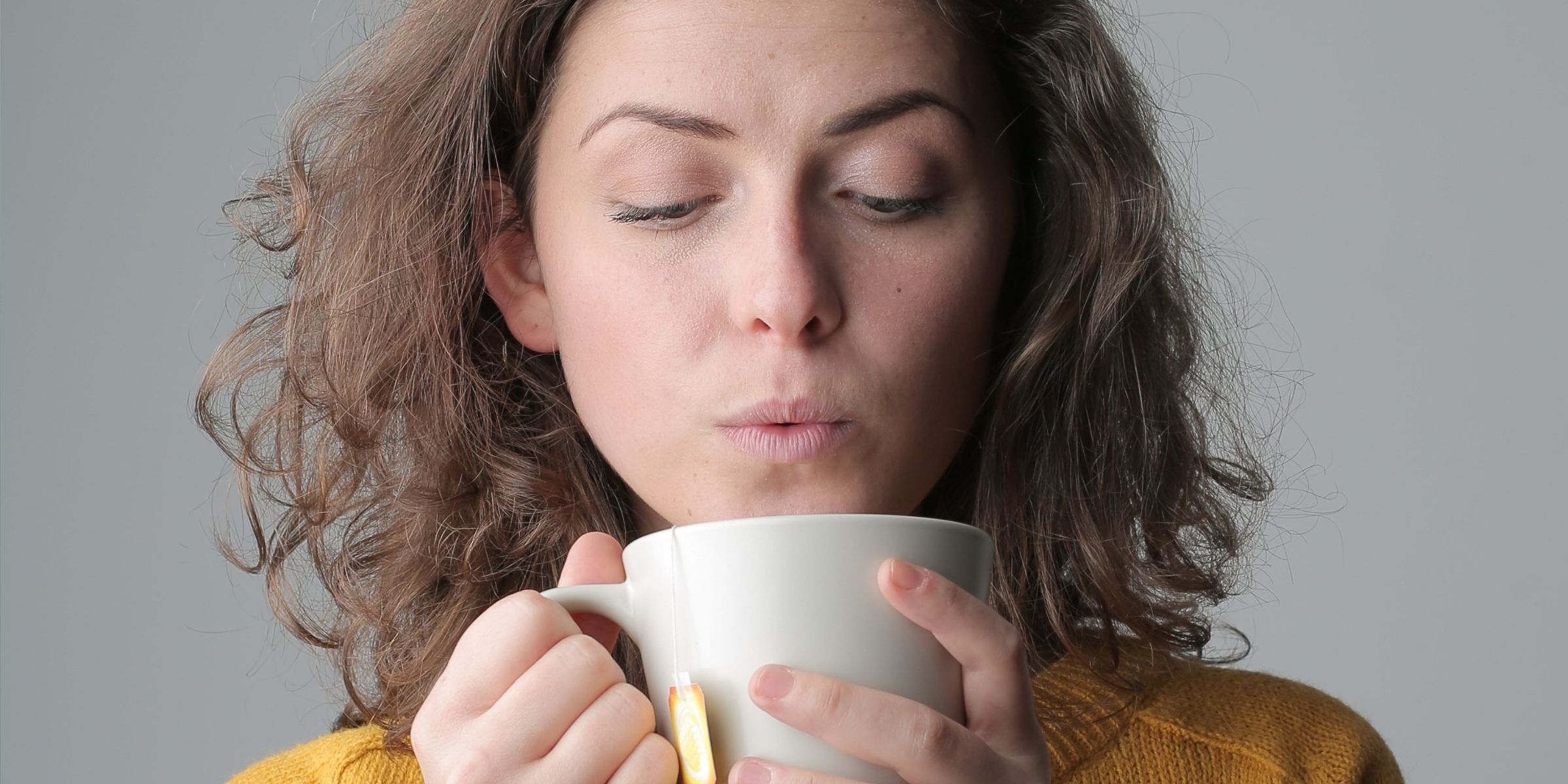 A woman blowing on a hot cup of tea | Source: Pexels