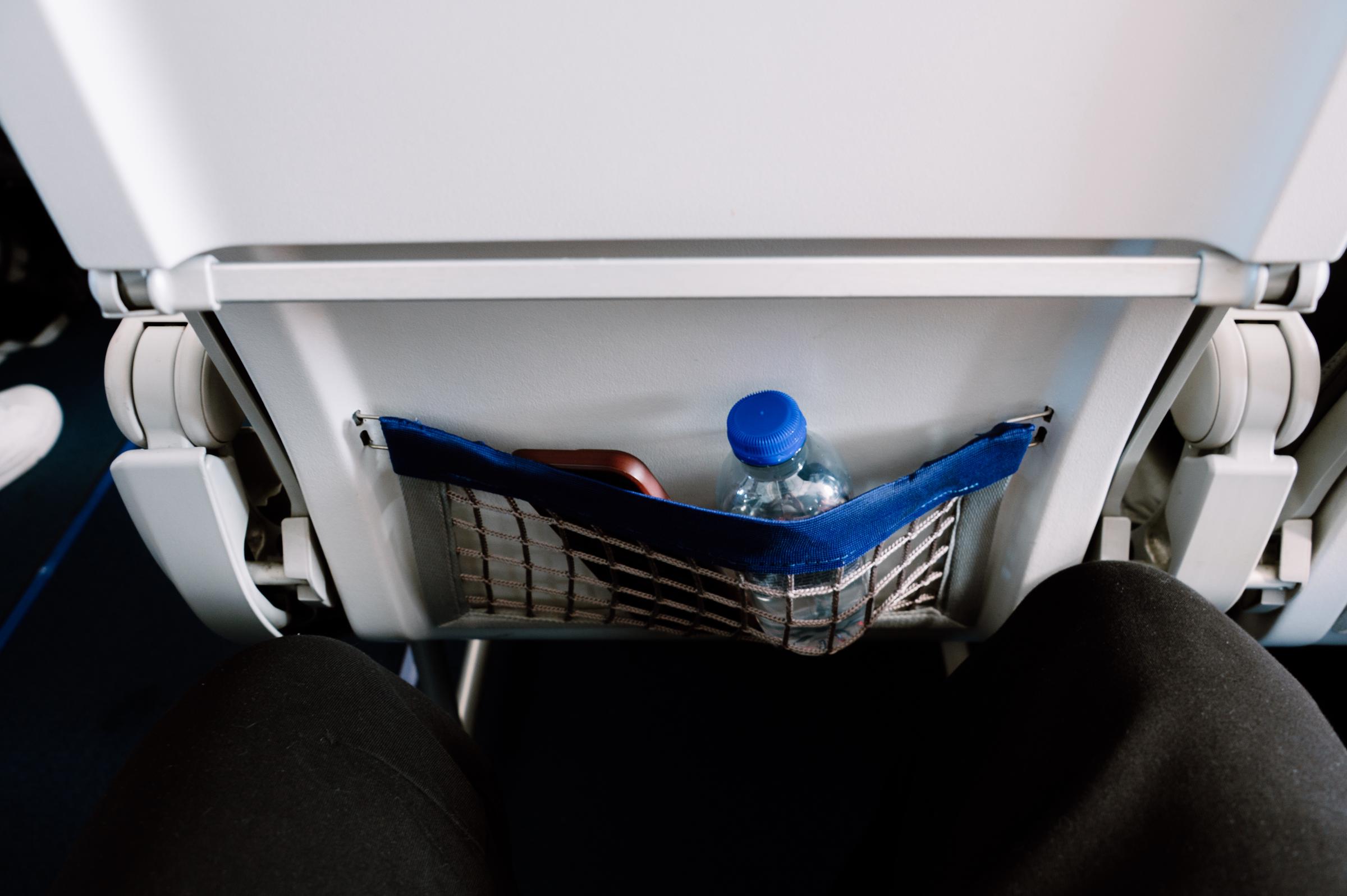 A phone and a water bottle in the seat pocket on a plane | Source: Getty Images