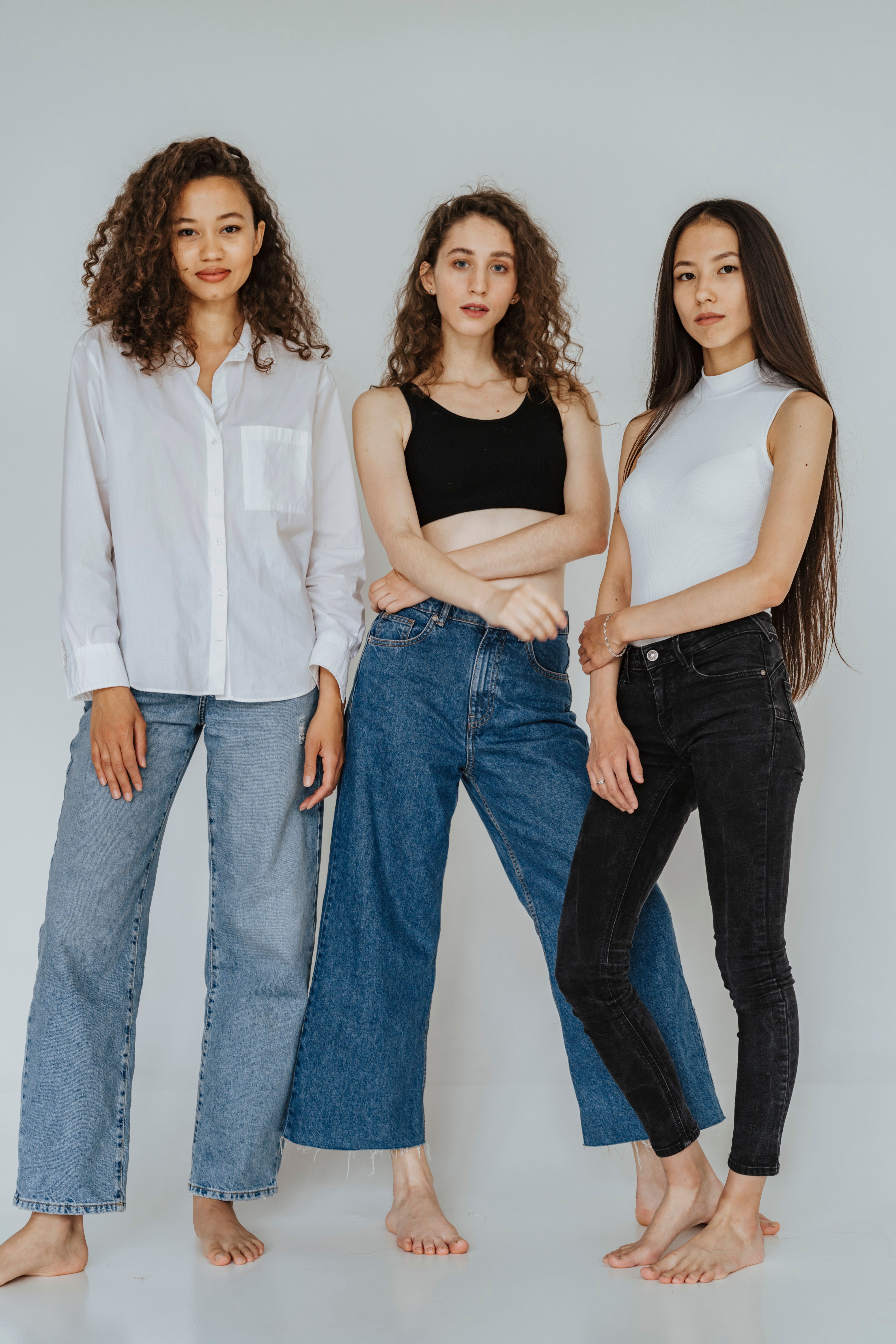 Three barefoot women wearing denim pants | Source: Pexels