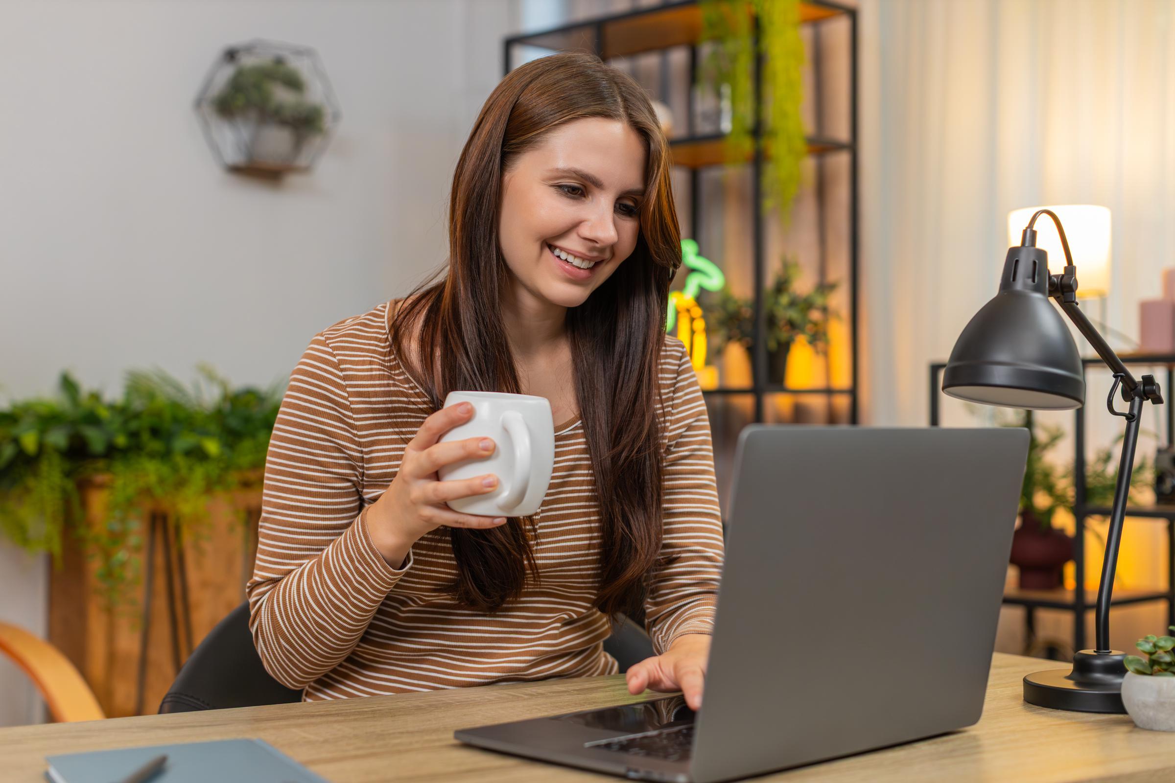 A young woman working at her laptop while drinking tea | Source: Getty Images