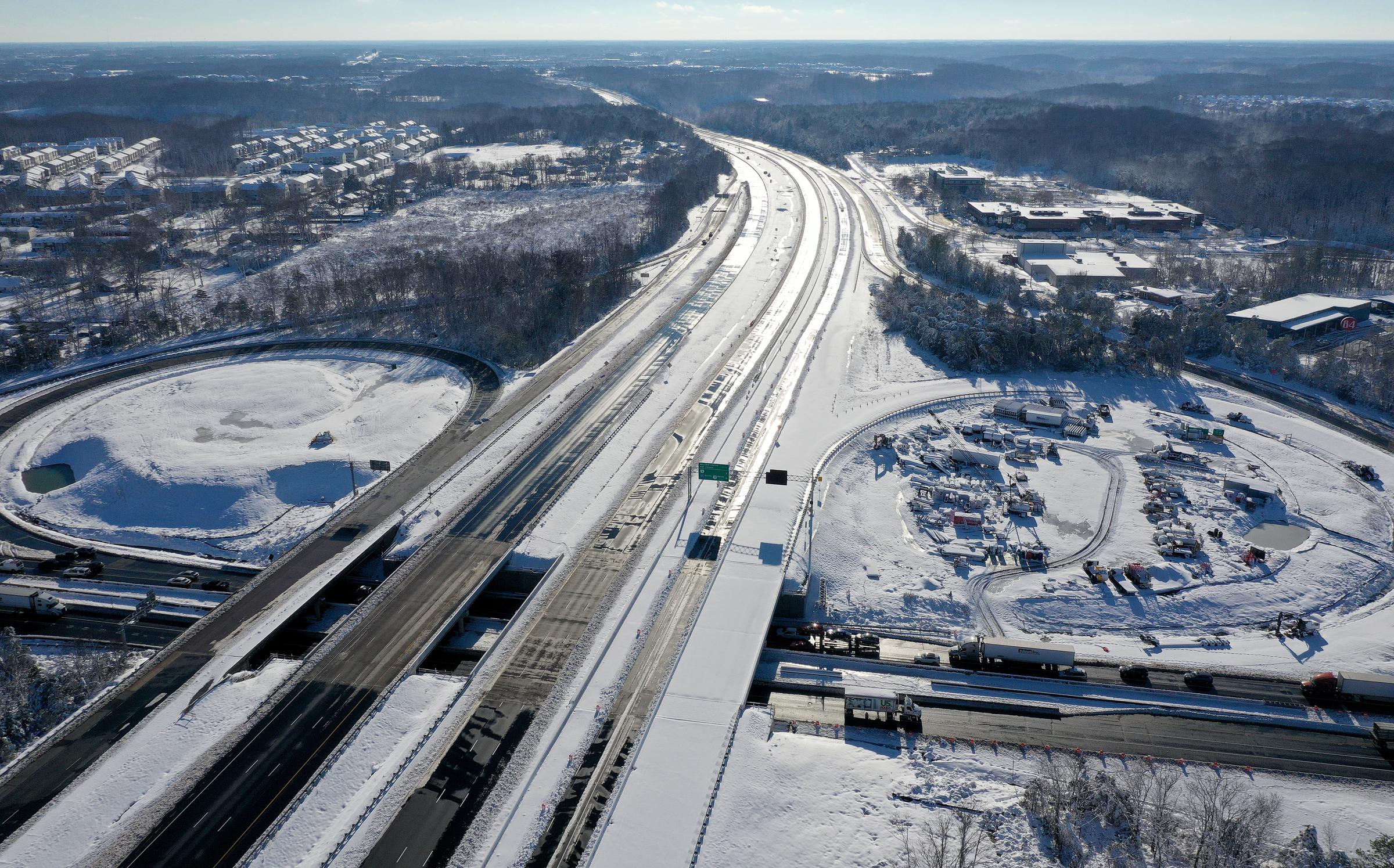 In an aerial view, north and southbound lanes of I-95 are empty as traffic moves along Warrenton Road while transportation crews attempt to clear the highway of snow and ice on January 4, 2022 in Fredericksburg, Virginia. | Source: Getty Images