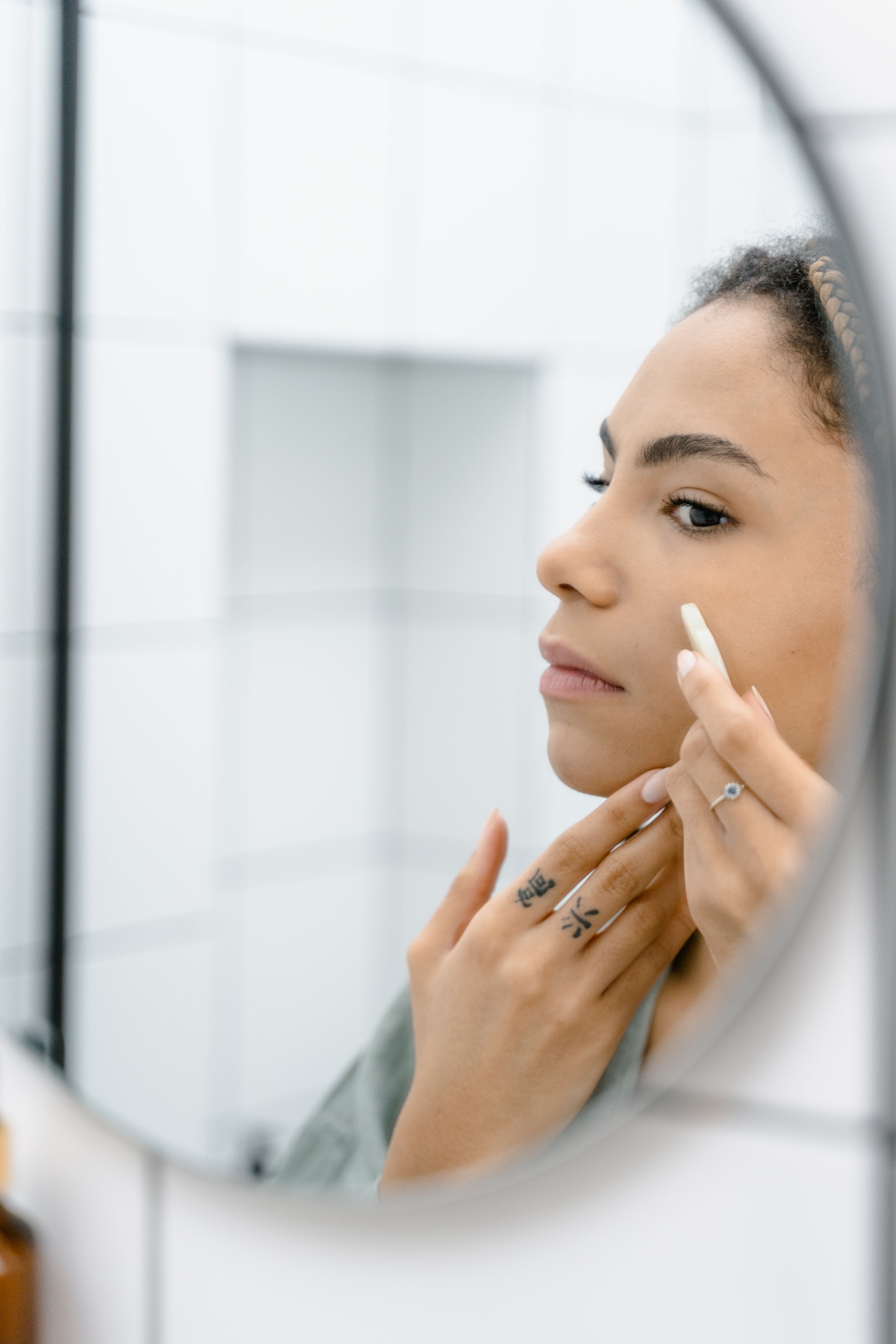 A woman doing her skincare routine in the mirror | Source: Pexels
