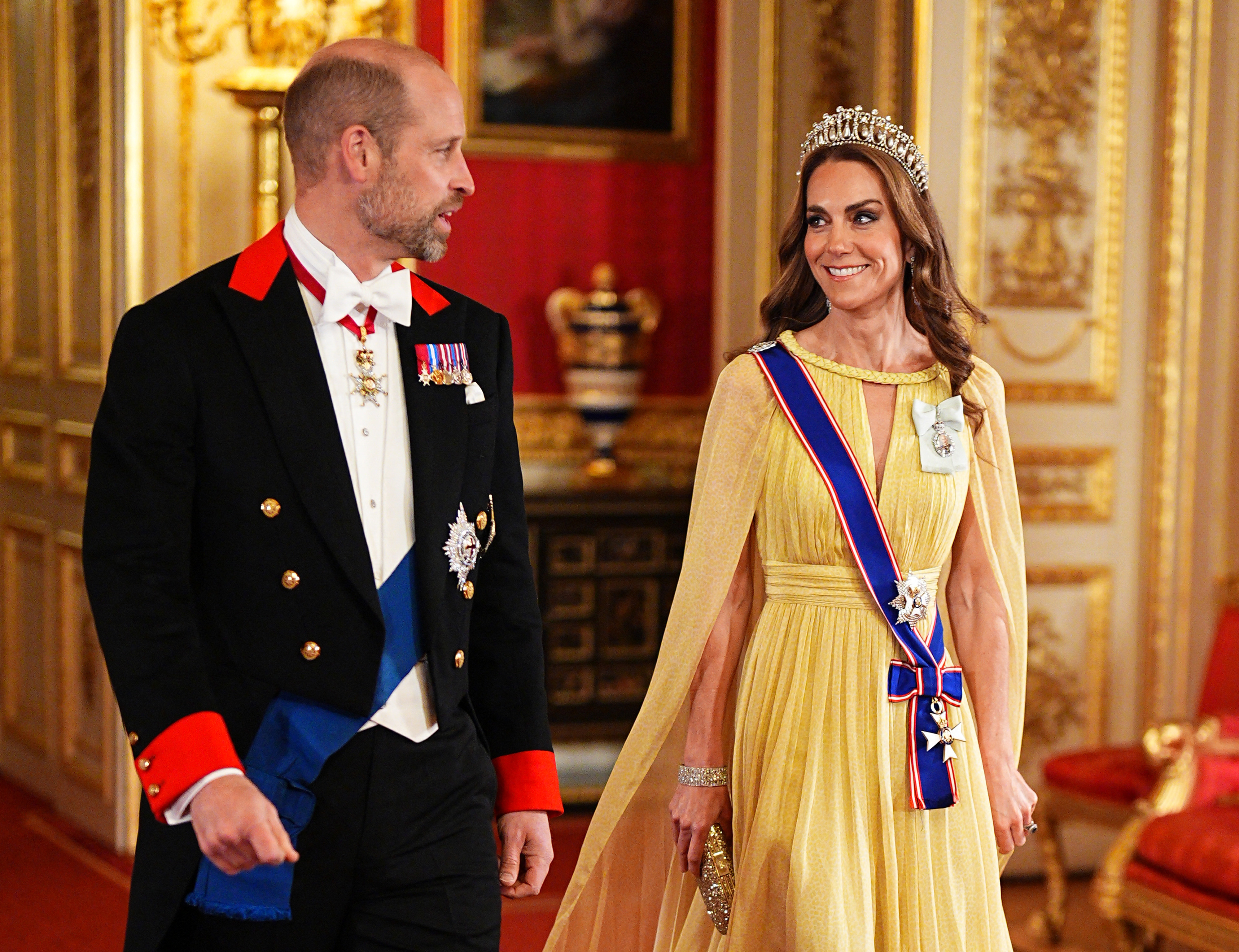 Catherine, Princess of Wales, exchanges a joyful smile with Prince William as they make their way through the grand reception rooms of Windsor Castle on October 20, 2026. Crowned with Queen Mary's Lover's Knot Tiara, Catherine stuns in a flowing buttercup-yellow Elie Saab cape gown adorned with the Royal Victorian Order sash and King Charles III's Royal Family Order, while William walks beside her in formal Windsor tailcoat attire featuring the Order of the Garter sash. | Source: Getty Images