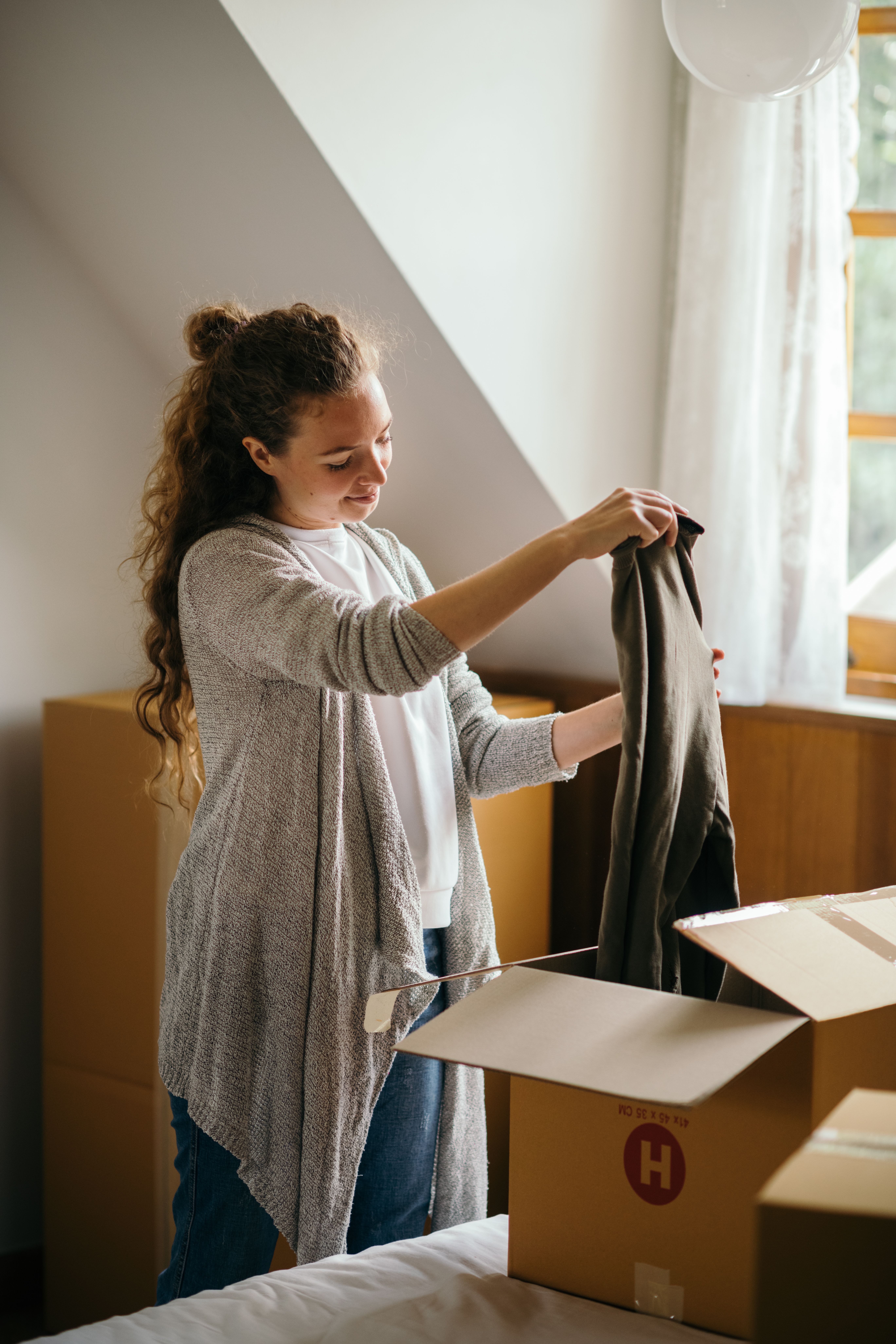 A woman storing a piece of clothing inside a box | Source: Pexels