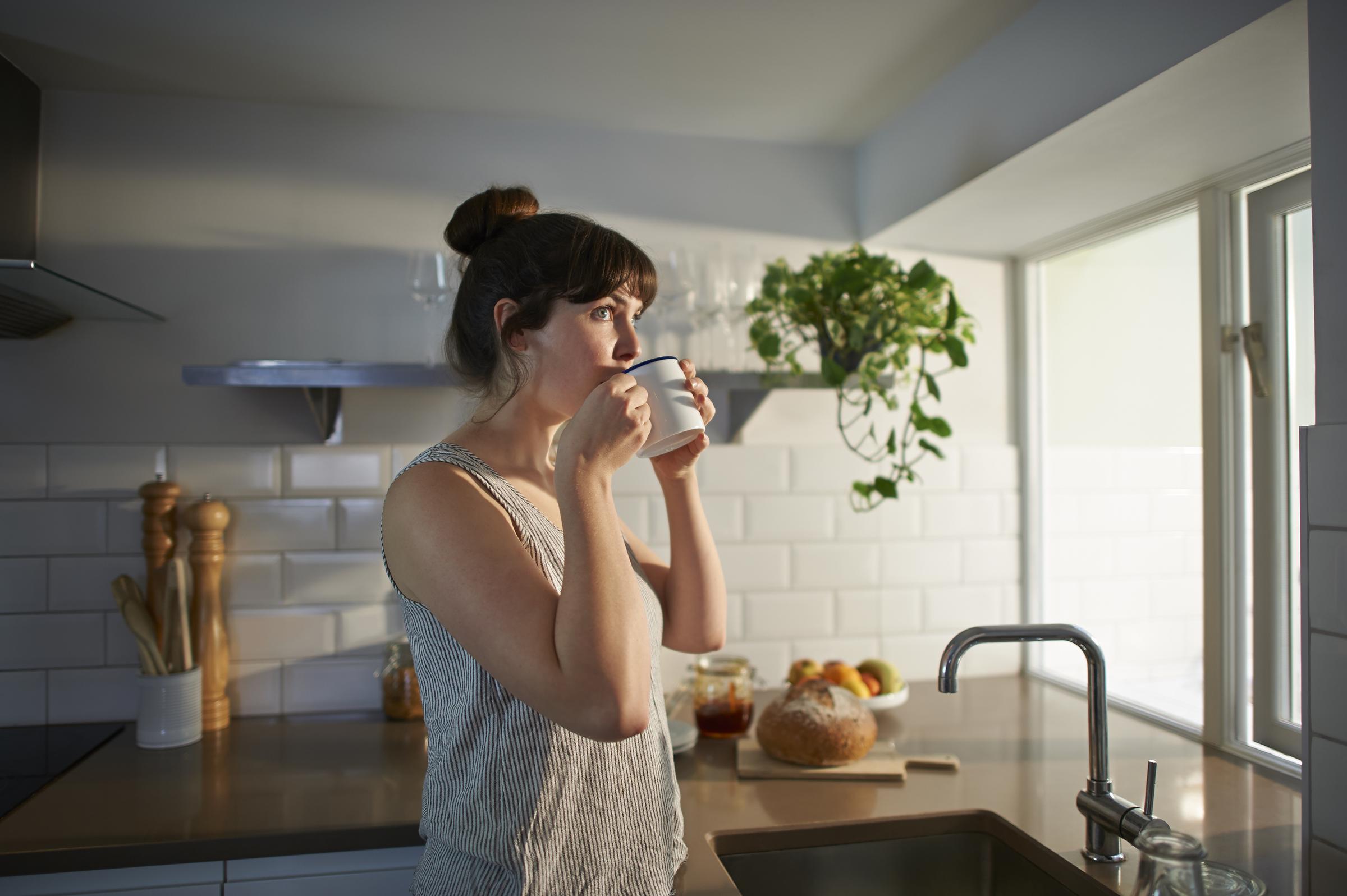 A woman drinks coffee from a mug in her kitchen | Source: Getty Images