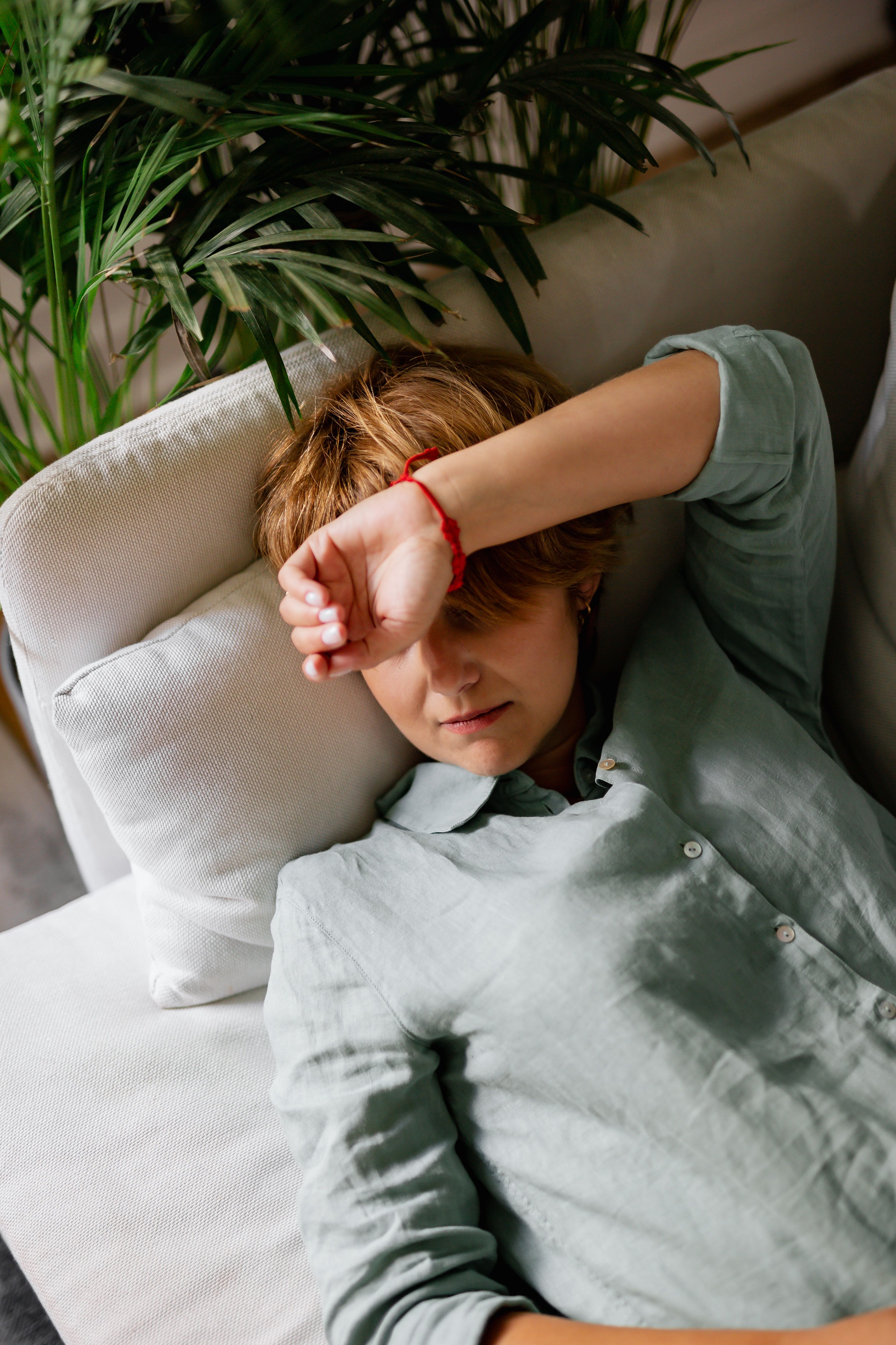 A woman lying down and shielding her eyes from the window light | Source: Pexels