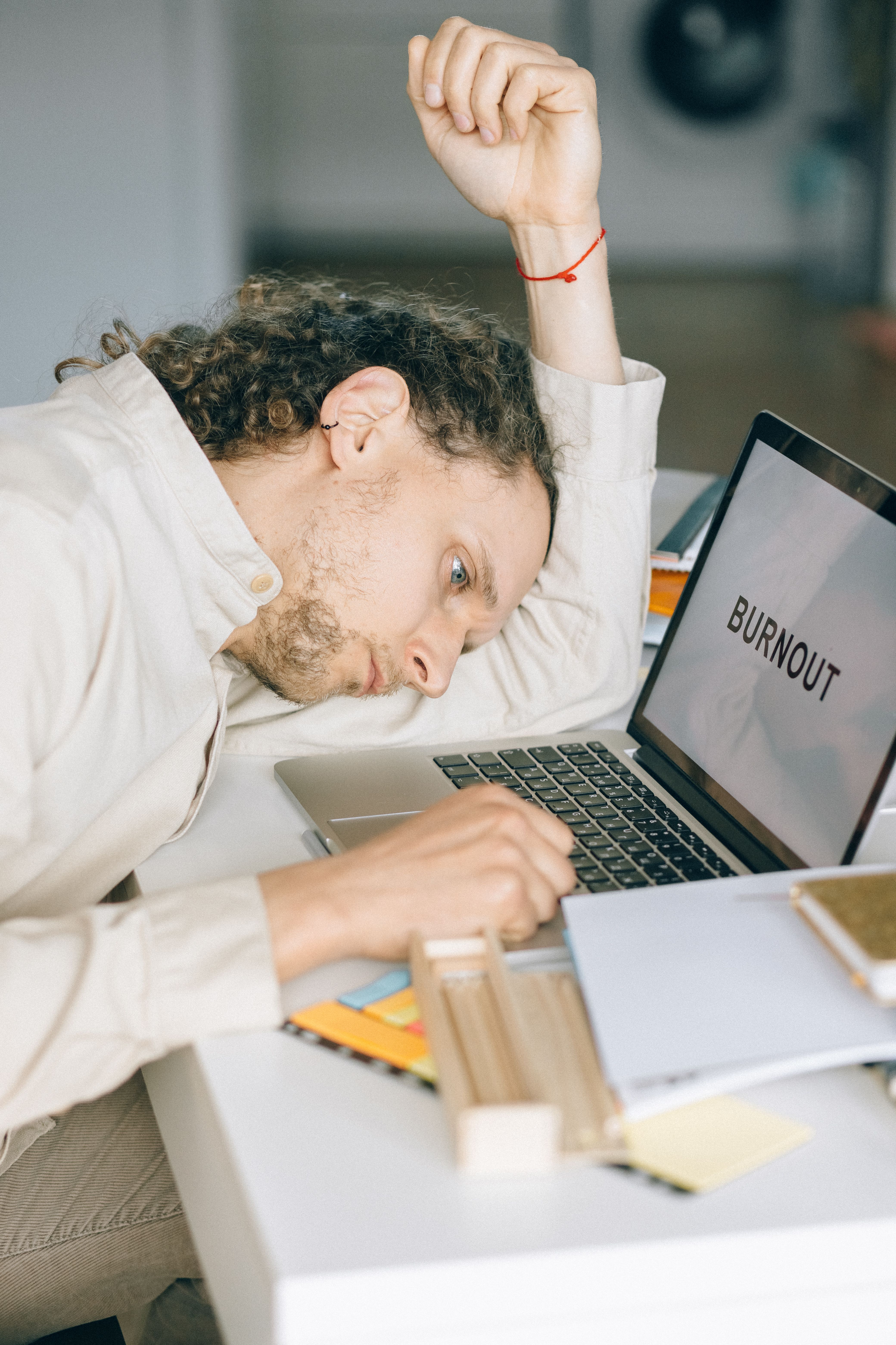 A man leaning on his desk with the word "burnout" on his laptop screen | Source: Pexels