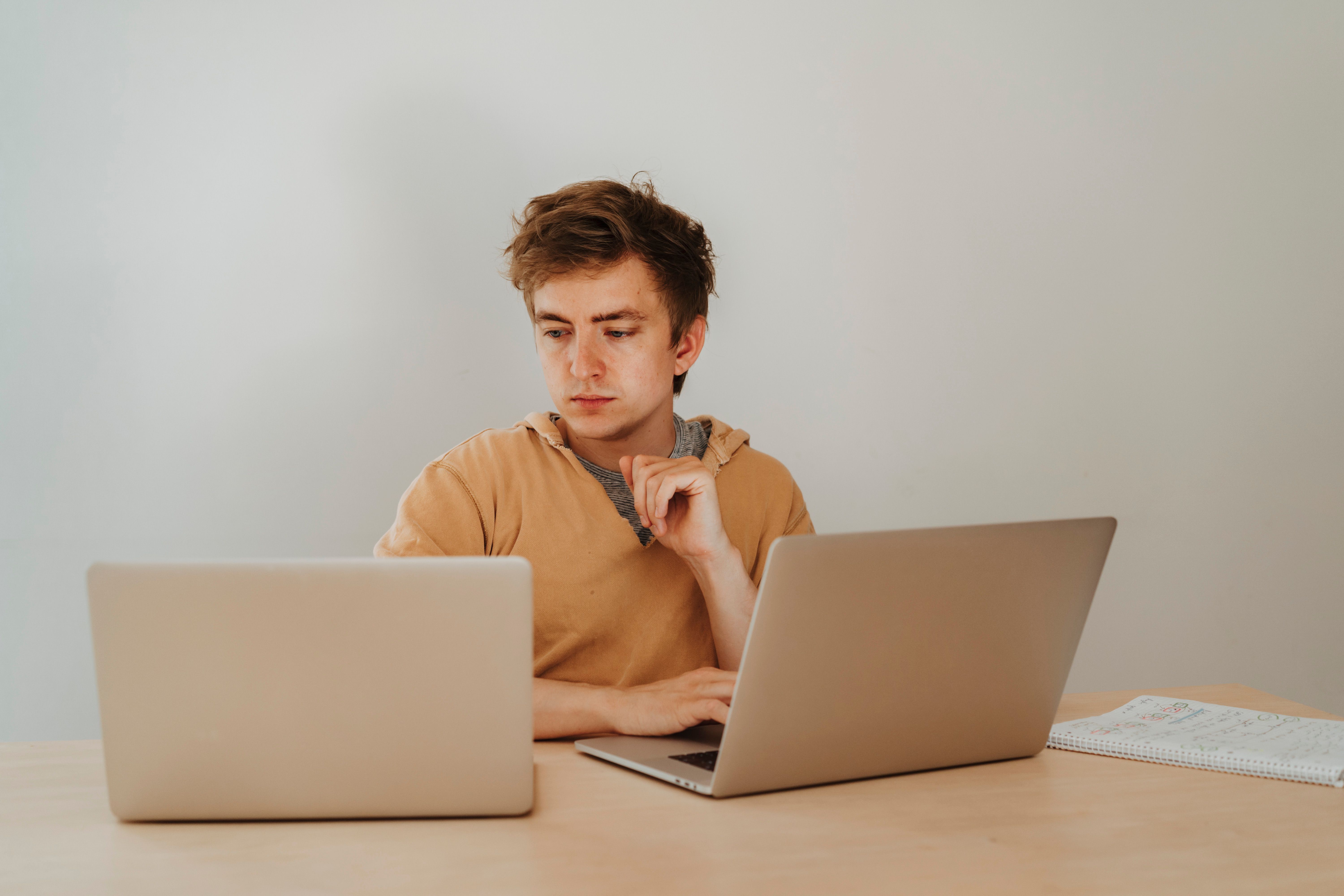 A young man working with two laptops | Source: Pexels
