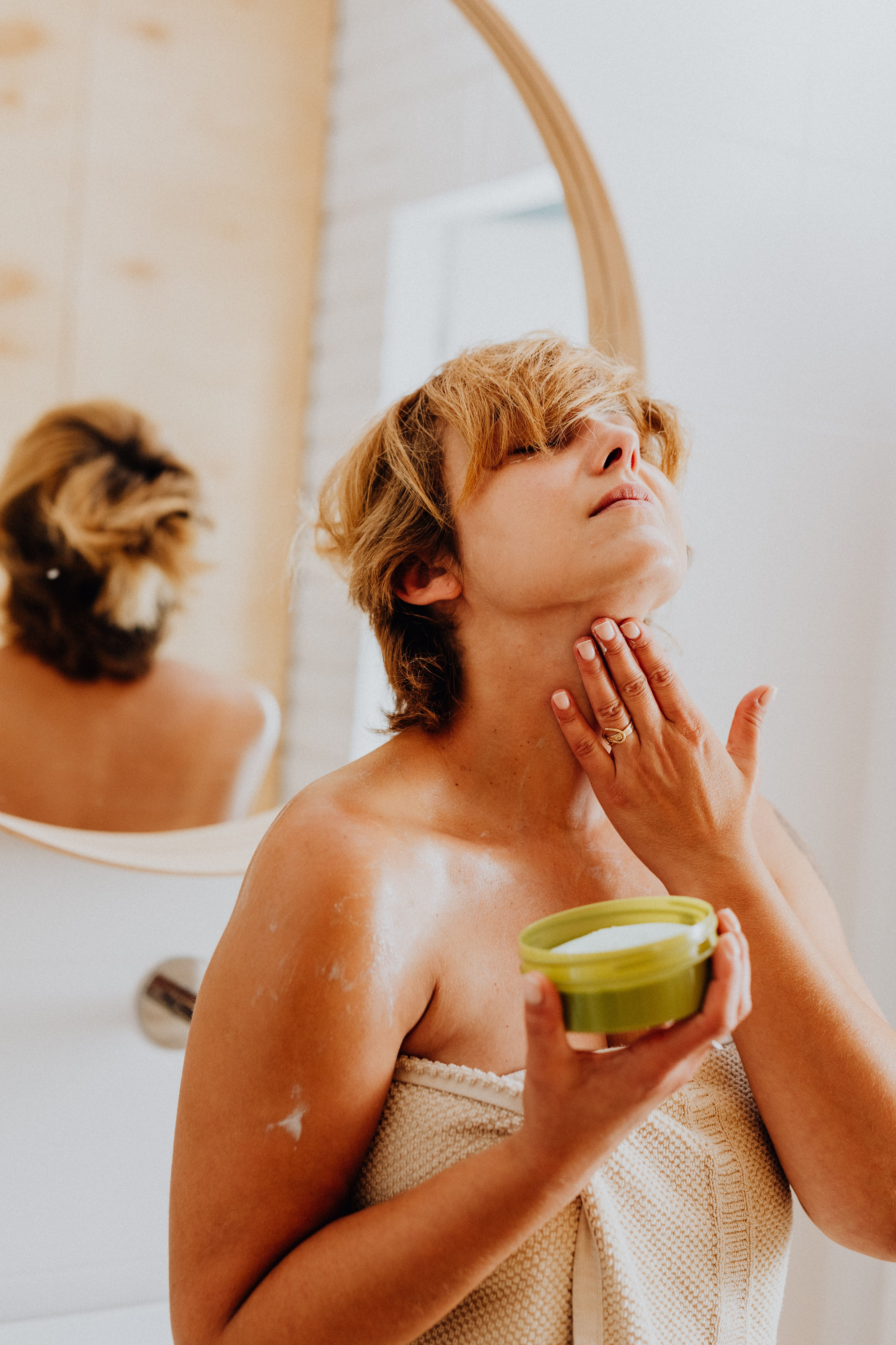 A woman applying cream on her neck | Source: Pexels