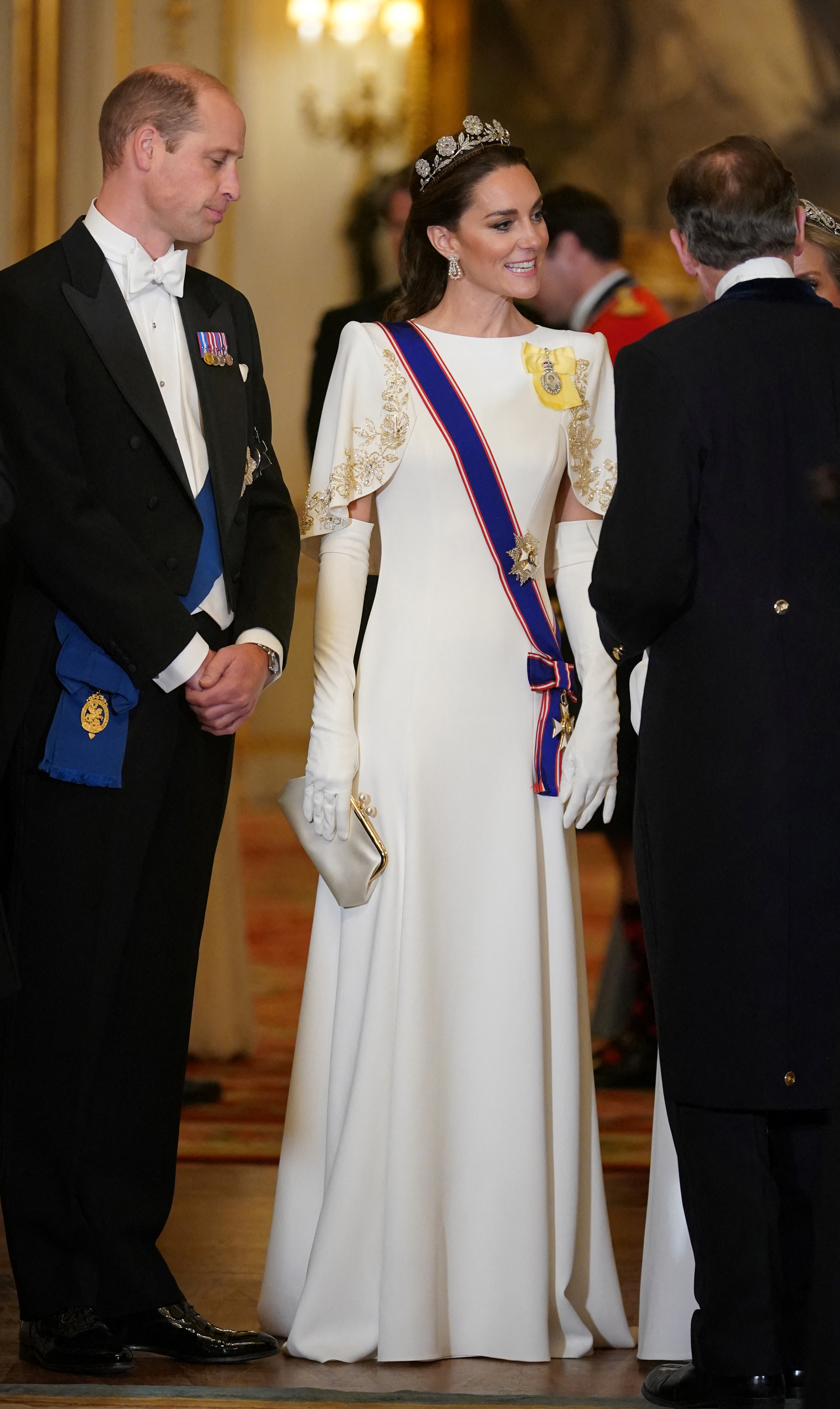 Prince William and Catherine, Princess of Wales, arrive for the State Banquet honoring South Korean President Yoon Suk Yeol and First Lady Kim Keon Hee at Buckingham Palace on November 21, 2023. Catherine dazzles in a bespoke white Jenny Packham gown detailed with gold-embroidered cap sleeves, white opera gloves, and the historic Strathmore Rose Tiara alongside Queen Elizabeth II's diamond earrings and royal insignia, as William stands beside her in a classic black tailcoat and white tie. | Source: Getty Images