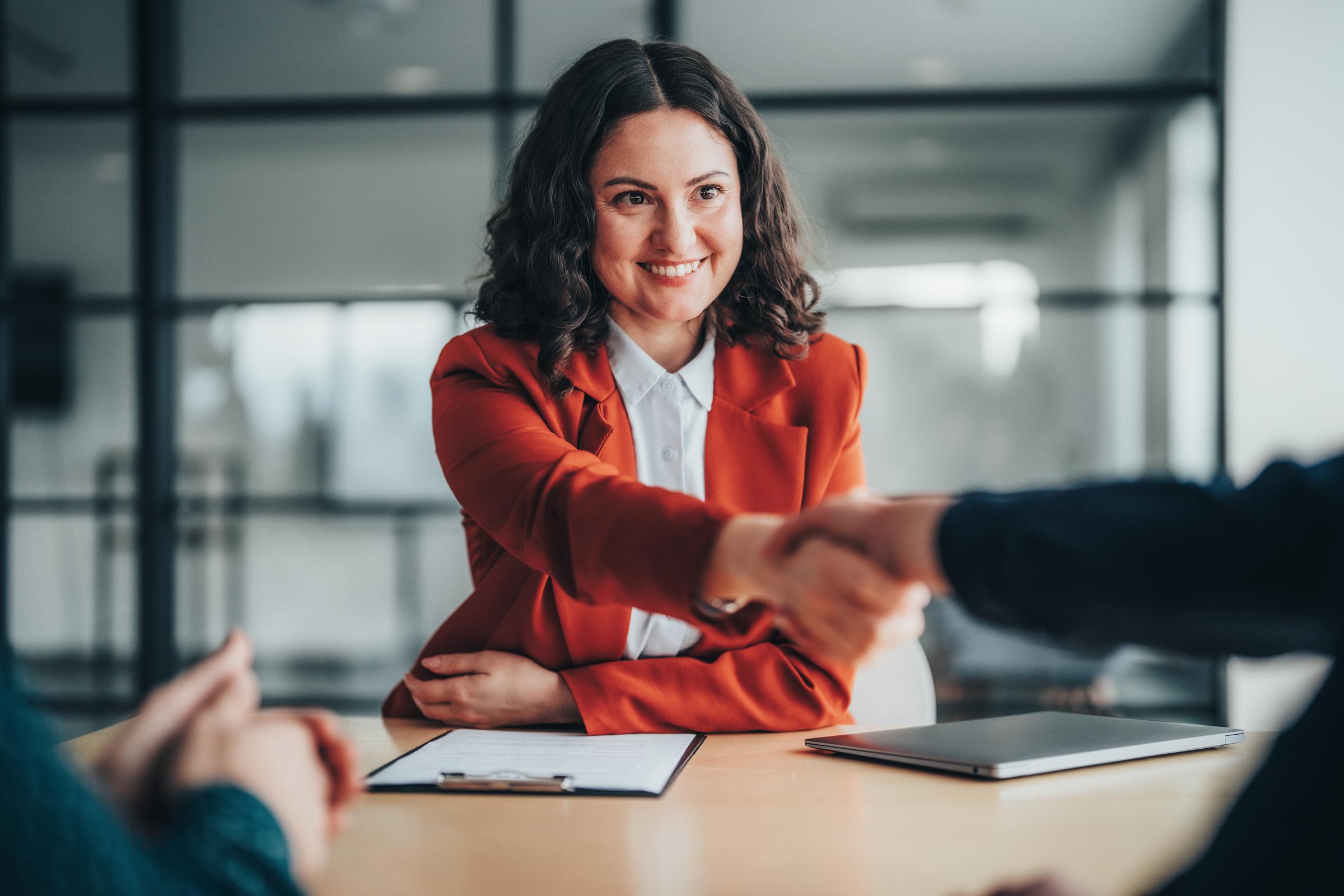 A woman shaking hands with recruiters | Source: Getty Images